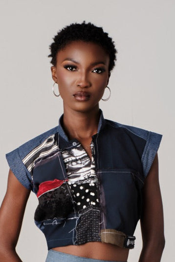 Model wearing a colorful, patchwork outfit with a vest and skirt on a plain background