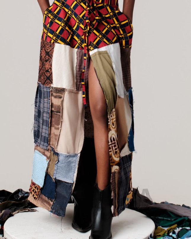 Person wearing a colorful, patchwork outfit with a plain background