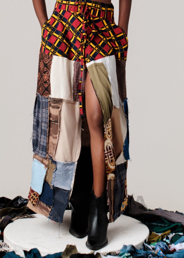 Person wearing a colorful, patchwork outfit with a plain background